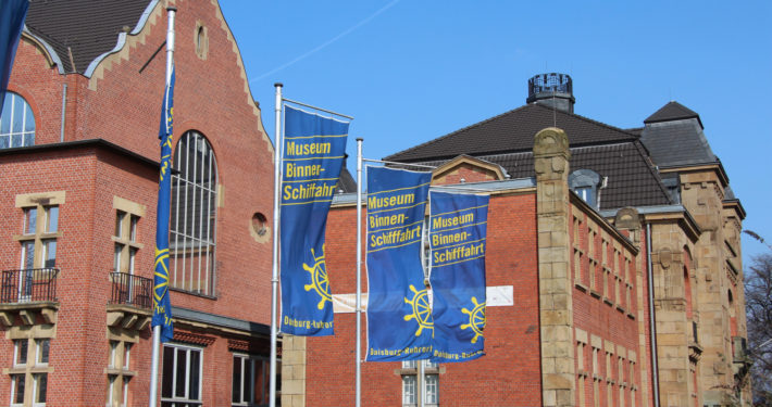 Blaue Fahnen vor dem roten Backsteingebäude des Binnenschifffahrtsmuseum Duisburg
