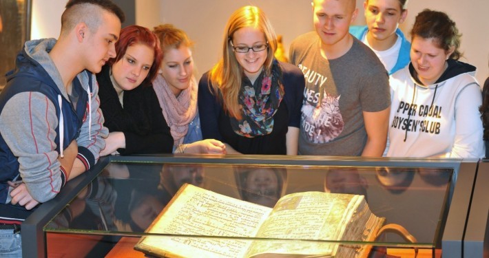 Eine Schülergruppe beschaut ein mittelalterliches Buch im Stiftsmuseum Xanten